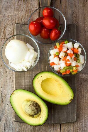 Raw avocado, tomato and onion in bowls
