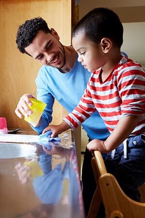 Father and son cleaning a kitchen work surface