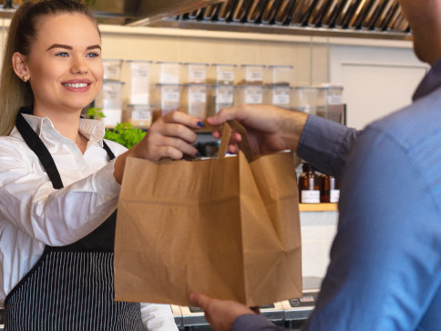 Woman handing over bag of groceries