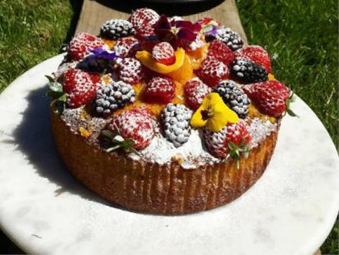 Cake topped with fresh fruit outside on grass